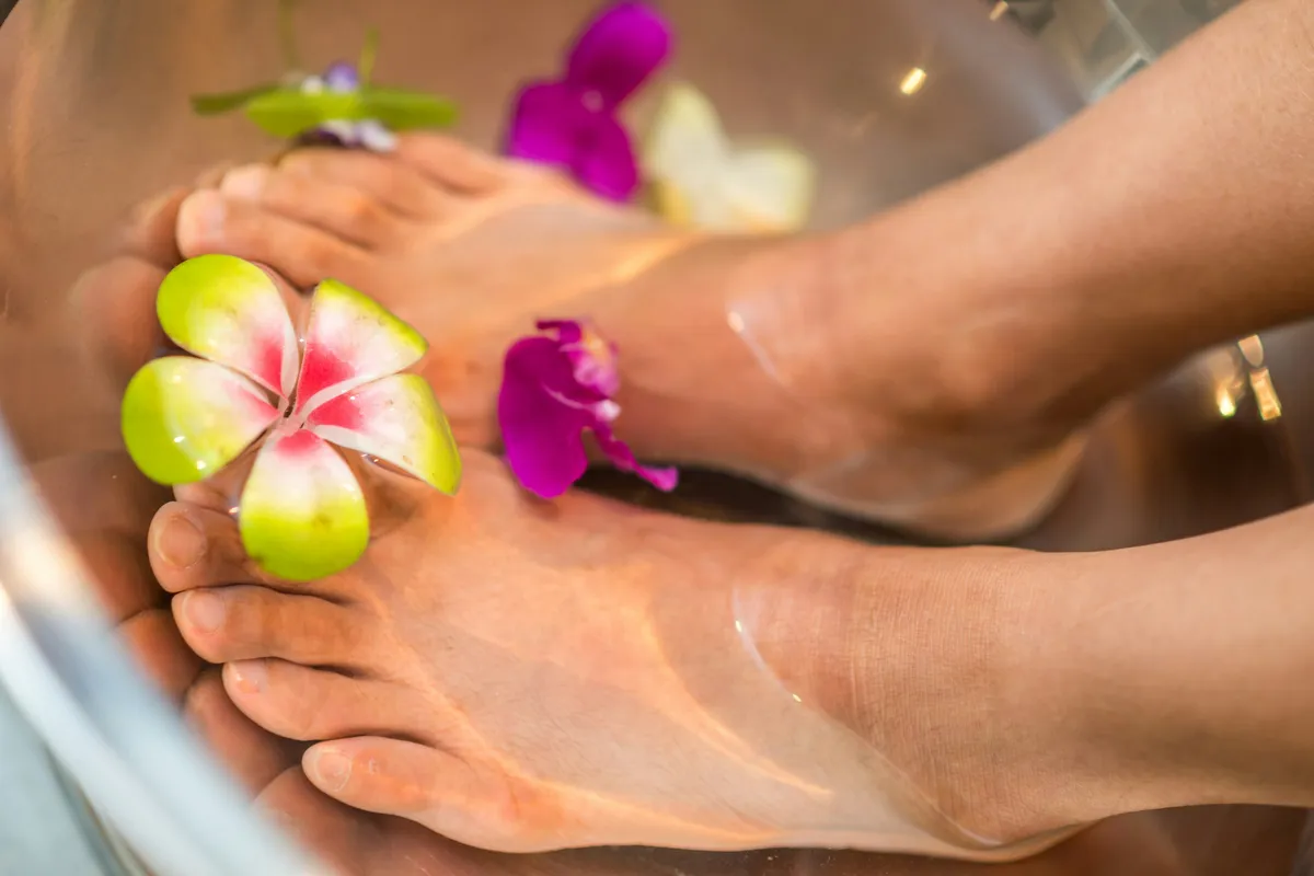 Pieds dans un bain parsemé de fleurs